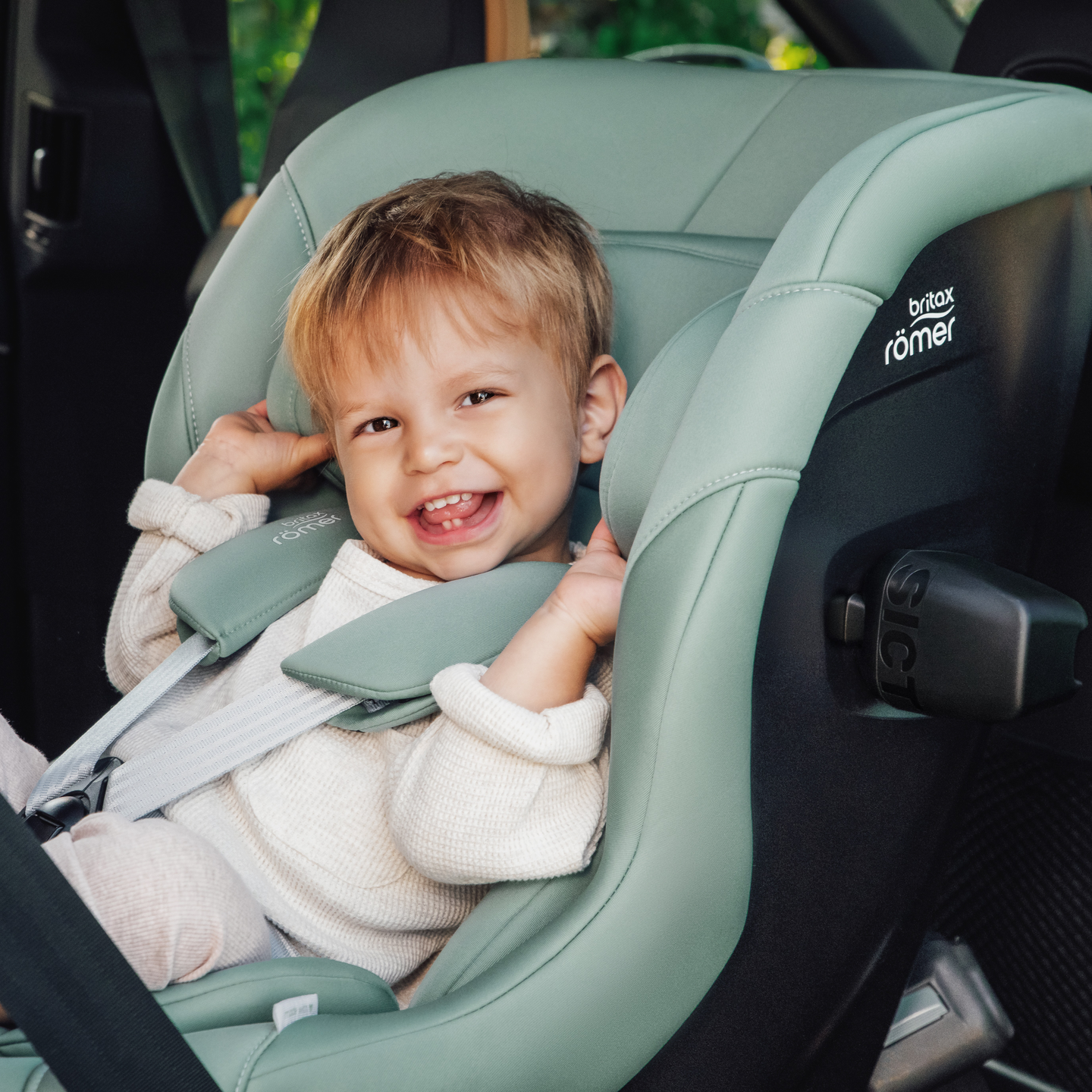 L&auml;chelndes Kleinkind im MAX-SAFE PRO Kindersitz in Jade Green im Auto gesichert.
